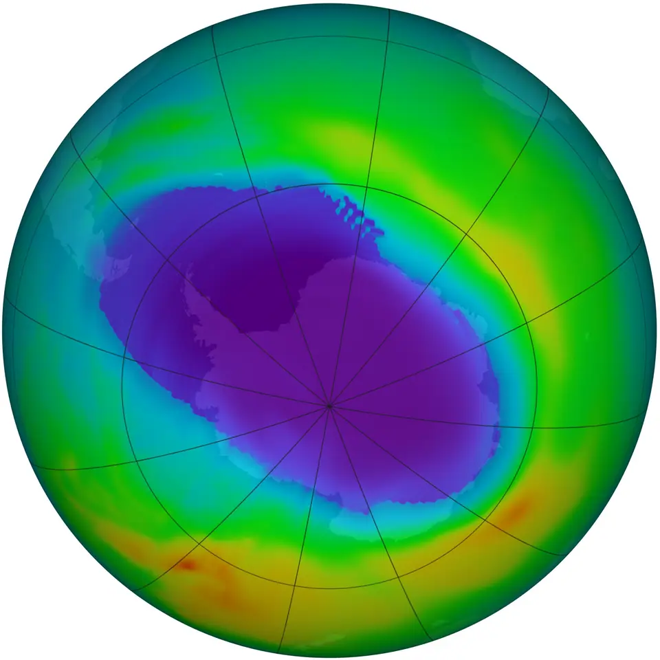 Mapa satelital del hemisferio sur visto desde el polo: una mancha violeta de ozono bajo cubre la Antártida, rodeada de verde y amarillo donde hay más ozono
