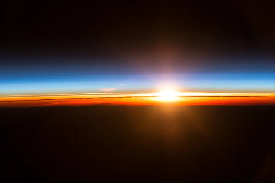 El Sol asoma sobre el borde de la Tierra, visto desde la Estación Espacial Internacional, con la capa fina y azulada de la atmósfera