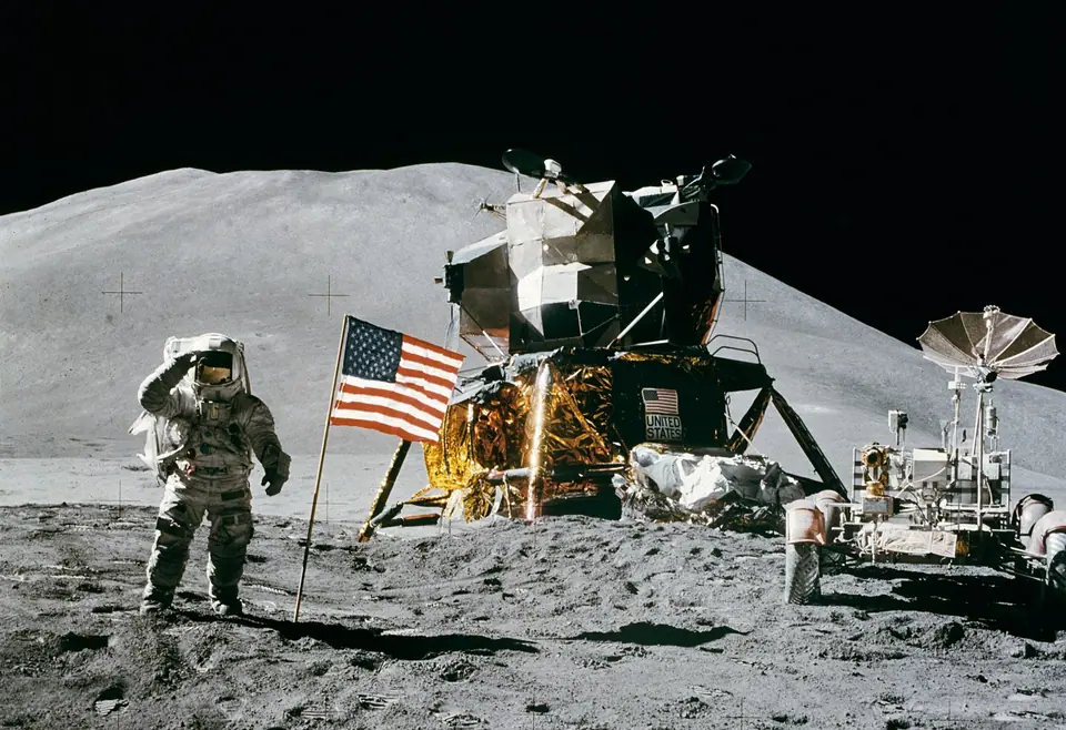 James Irwin, del Apolo 15, saluda junto a la bandera, con el módulo lunar y el vehículo lunar detrás y el monte Hadley al fondo