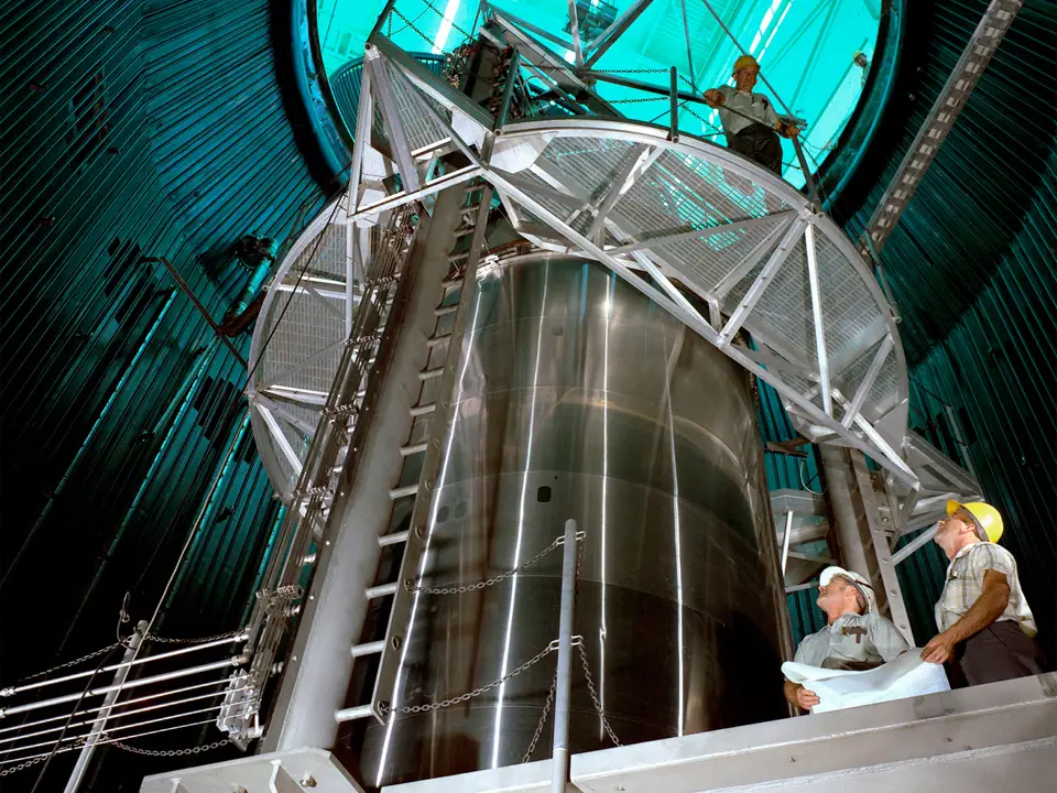 Una etapa de cohete Centaur dentro de la gigantesca cámara de vacío B-2 de la NASA, en Ohio, con técnicos al pie