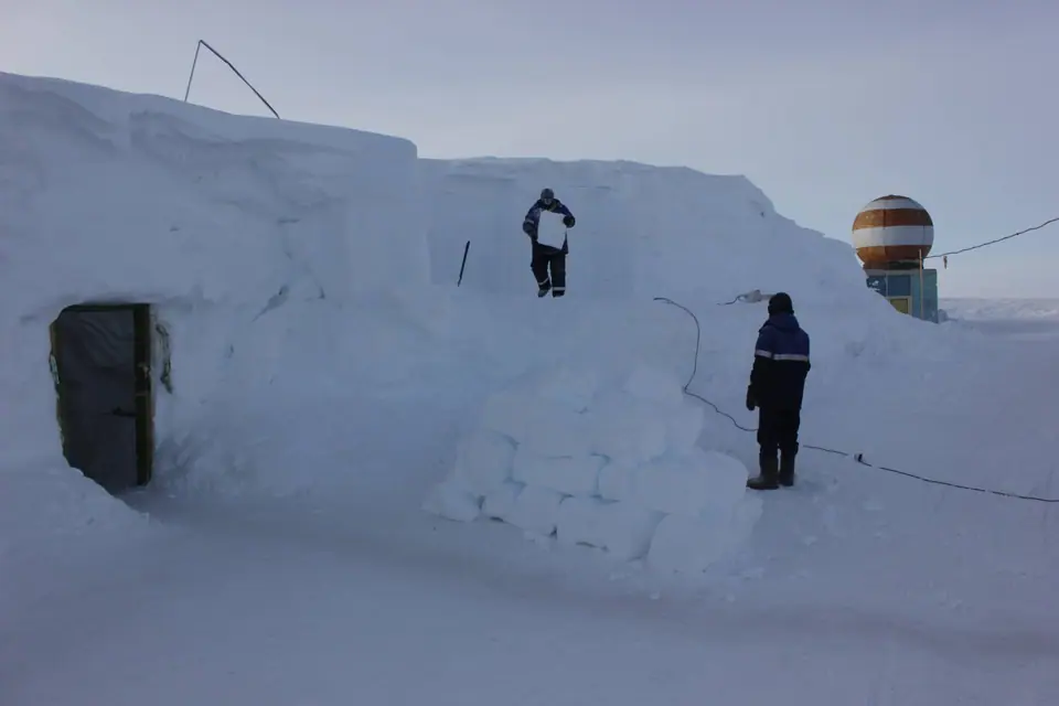Personal de la estación Vostok, en la Antártida, cortando bloques de nieve junto a la cúpula de un radar