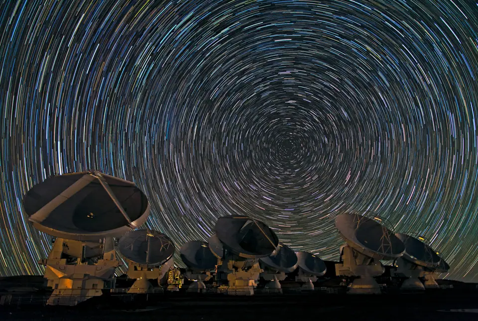 Trazos circulares de las estrellas alrededor del polo sur celeste sobre las antenas del observatorio ALMA, en Chile, en una foto de larga exposición