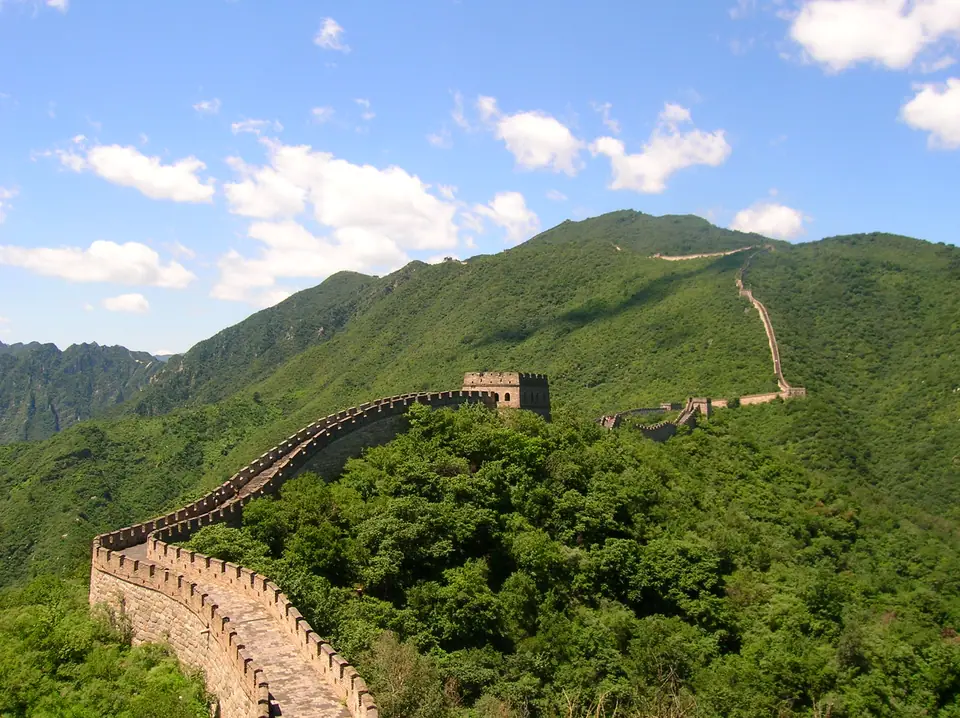 La Gran Muralla china serpentea por la cresta de montañas cubiertas de bosque, como una línea fina en el paisaje