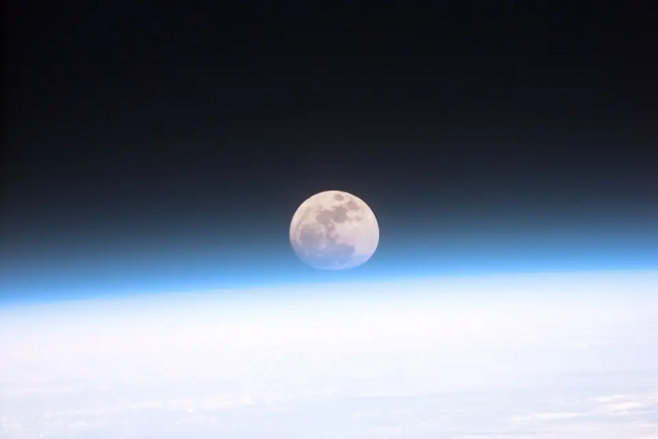 Luna llena sobre el borde de la Tierra, vista a través de la atmósfera desde la órbita