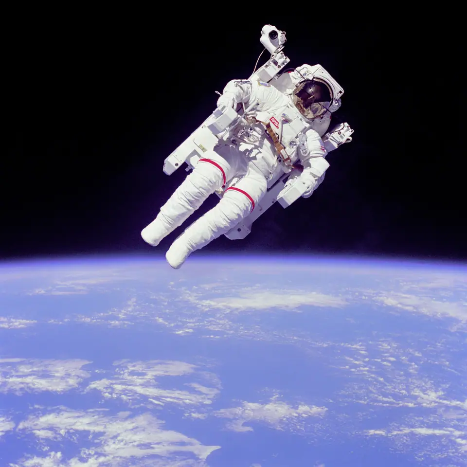 El astronauta Bruce McCandless flota solo en el espacio con su traje presurizado y una mochila propulsora, con la Tierra de fondo, en 1984