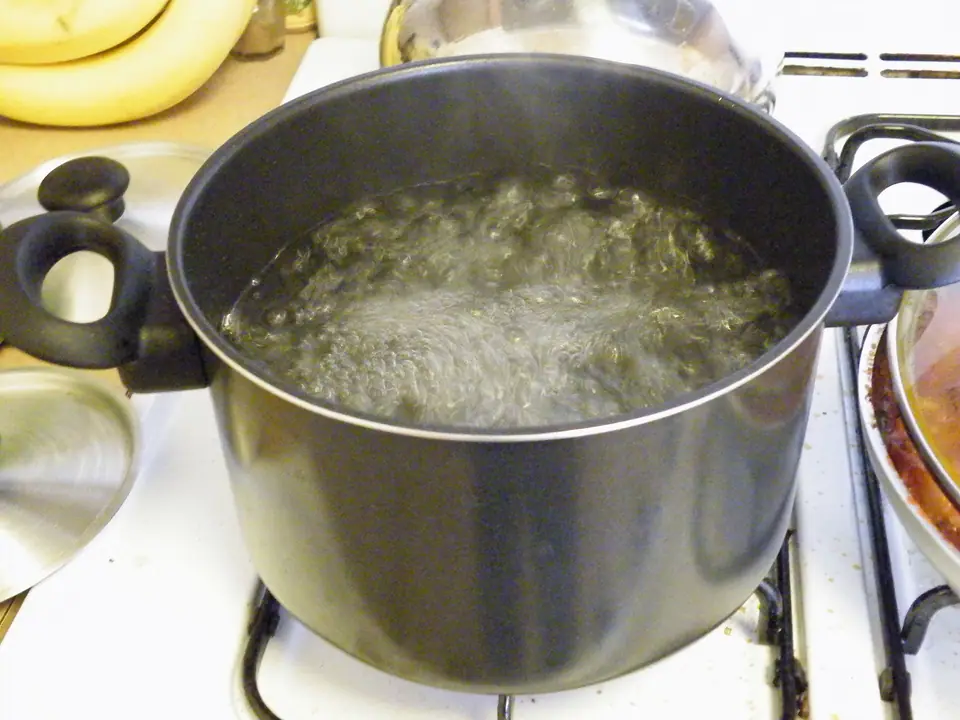 Olla con agua en plena ebullición sobre la cocina, con burbujas que suben desde el fondo