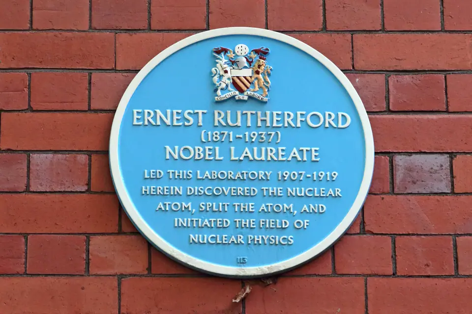 Placa azul en una pared de ladrillo de la Universidad de Manchester que recuerda que Ernest Rutherford descubrió allí el átomo nuclear