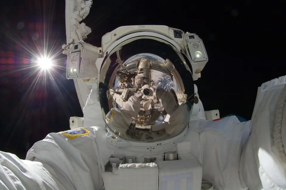 El astronauta Akihiko Hoshide en una caminata espacial junto a la Estación Espacial Internacional, con el Sol blanco brillando a la izquierda